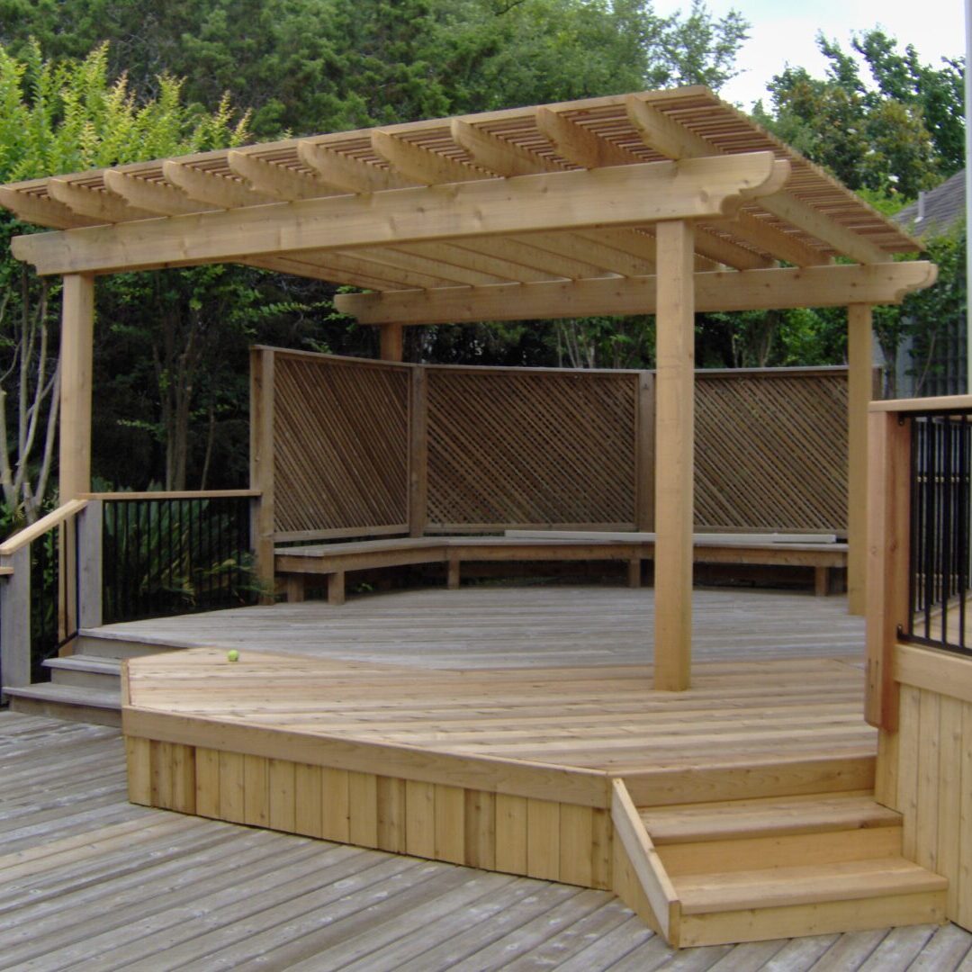 A wooden deck with benches and a pergola.